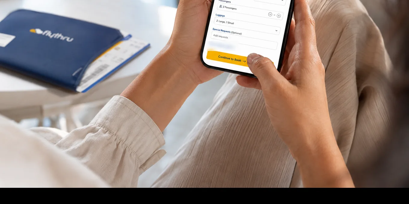 A passenger booking their FlyThru home check-in on a phone, with a FlyThru documents wallet on the table