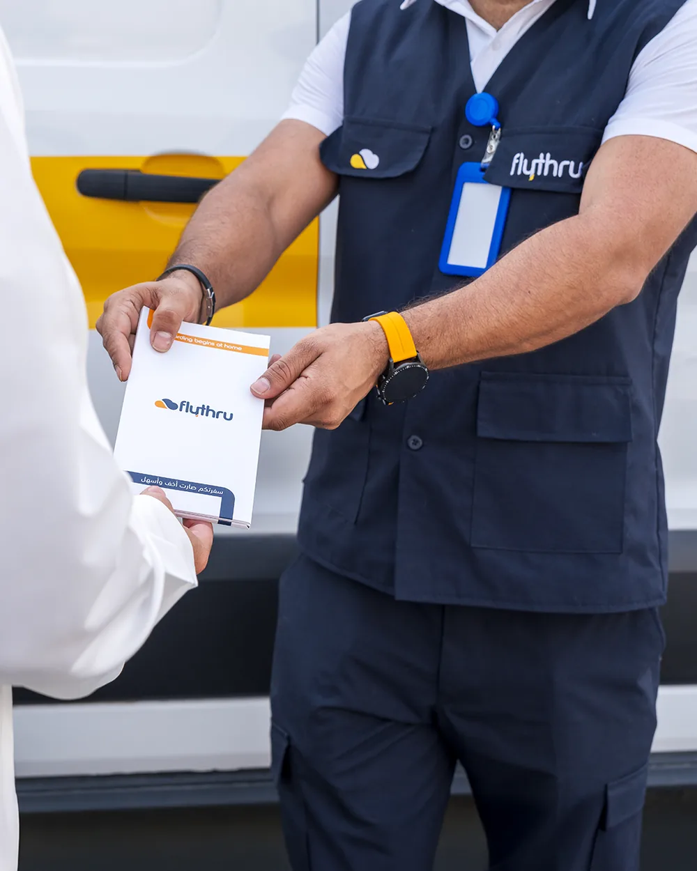 A FlyThru agent handing a passenger their boarding documents wallet