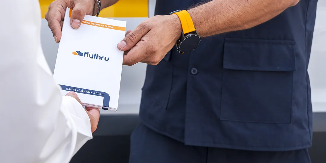 A FlyThru agent handing a passenger their boarding documents wallet